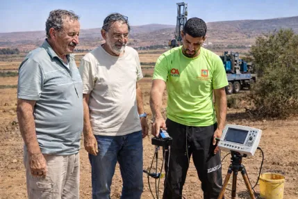 détection eau souterraine Maroc équipe géophysique avec appareil et foreuse arrière plan