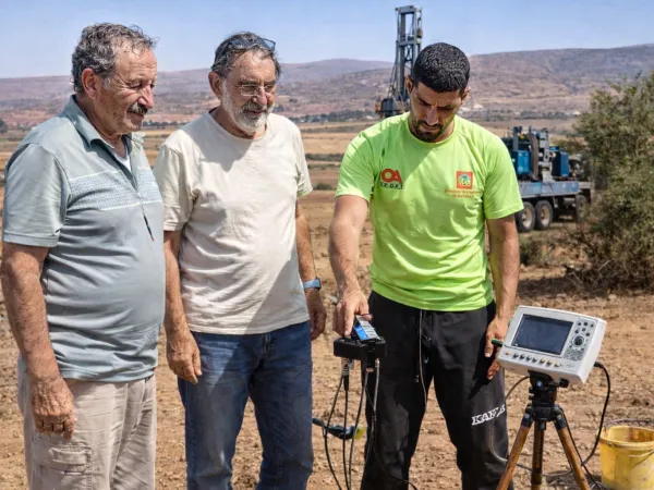 détection eau souterraine Maroc équipe géophysique avec appareil et foreuse arrière plan